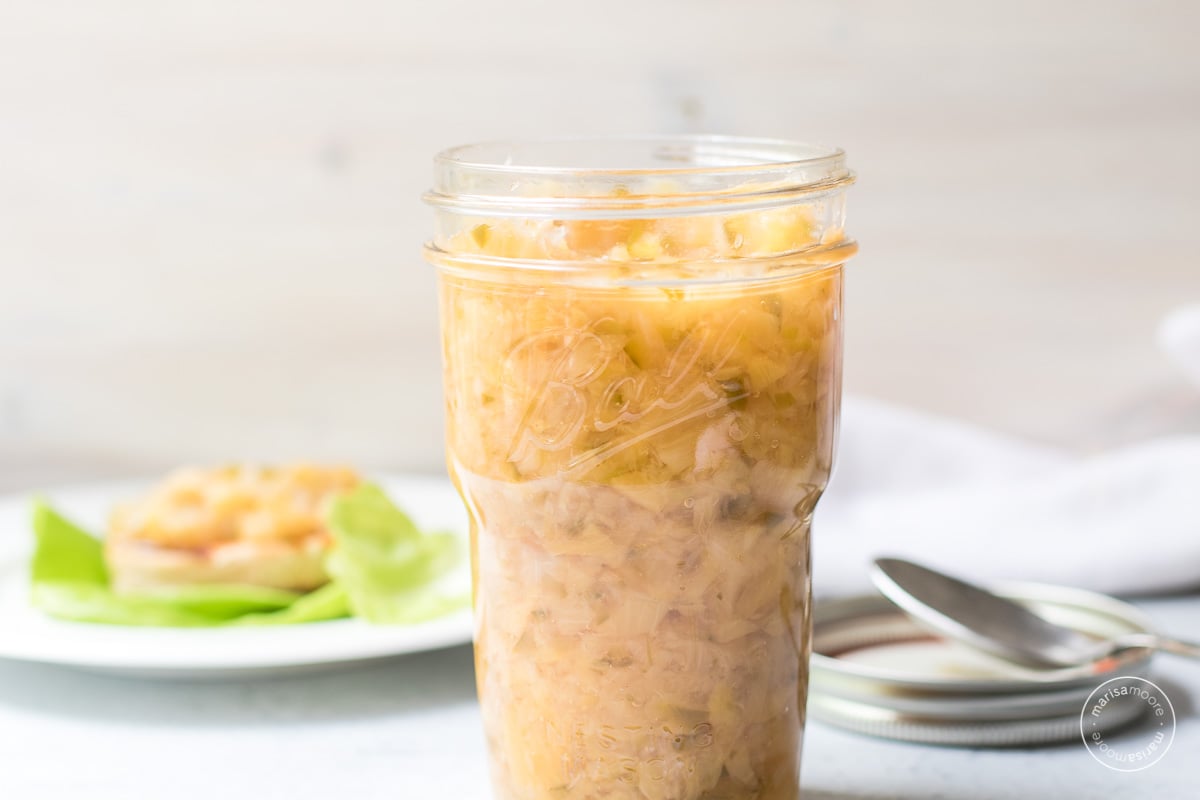 open jar of relish with a salmon burger on lettuce in the background