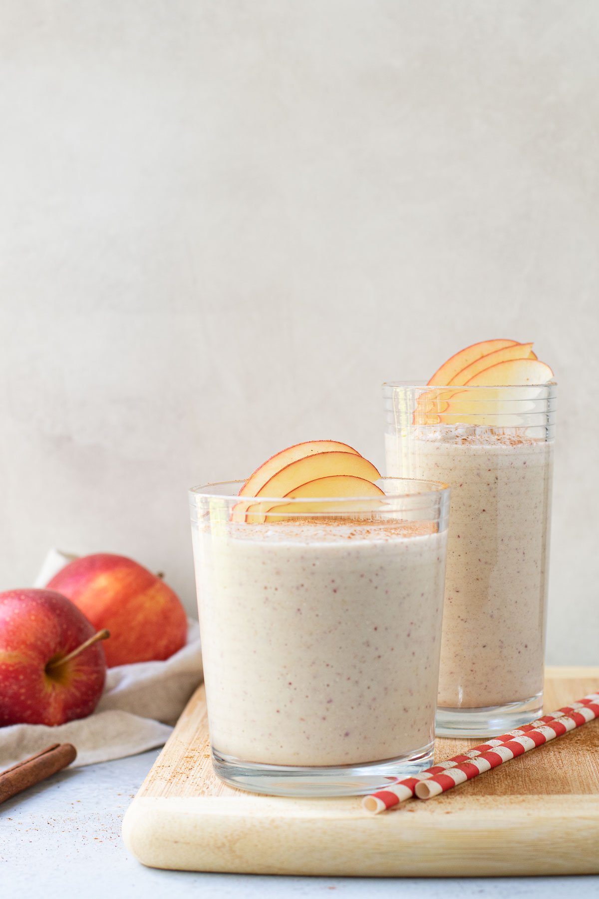 Smoothie in two glasses with apples in the background