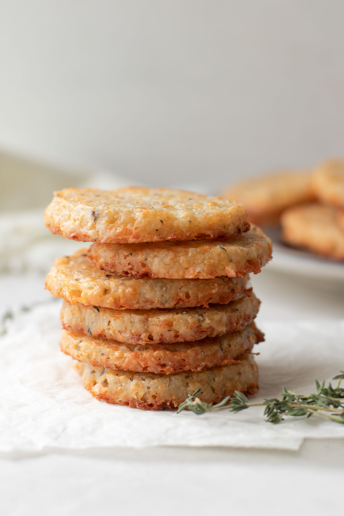 6 cheese cookies stacked with a sprig of thyme