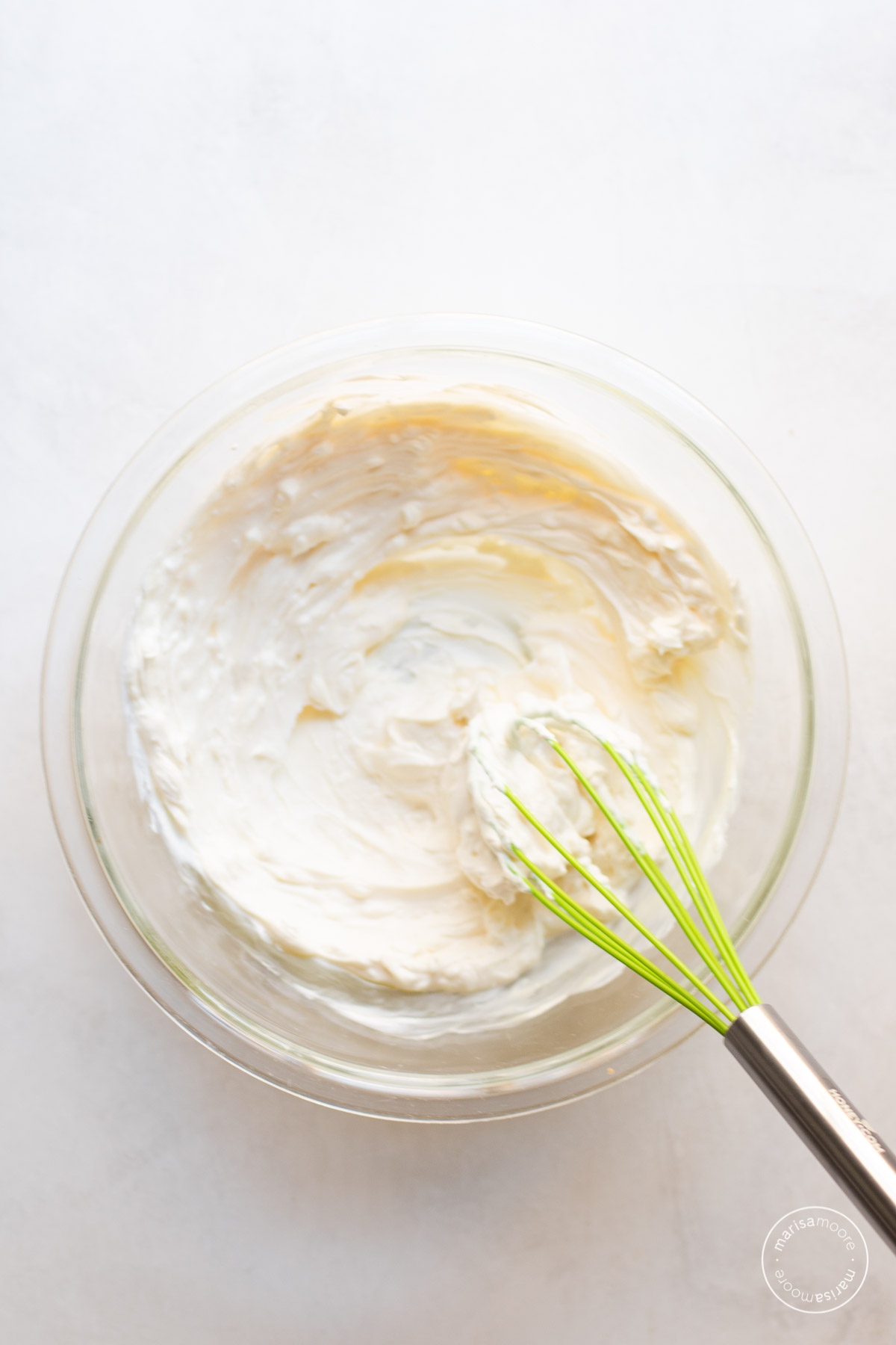 Smooth cream cheese yogurt mix in a bowl with a whisk.