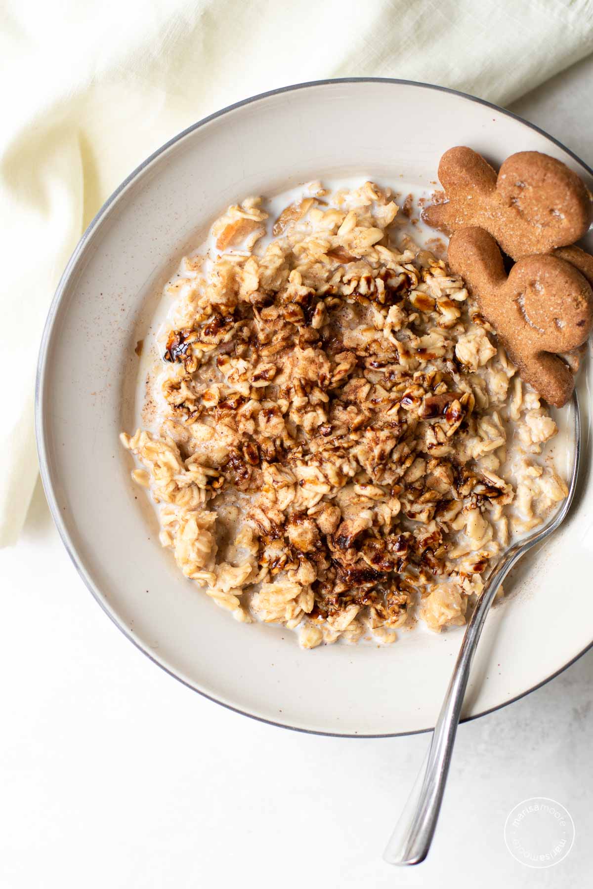 Gingerbread flavored oats in a bowl drizzled with molasses and garnished with gingerbread cookies