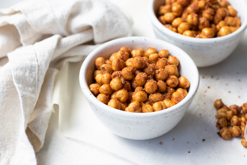 Side view of air fryer chickpeas in a white bowl with beige napkin.