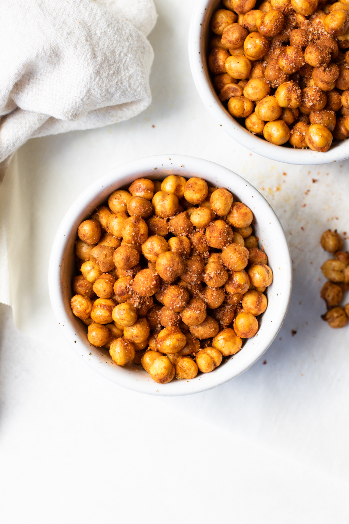 Overhead view of air fryer chickpeas in a white bowl with beige napkin.