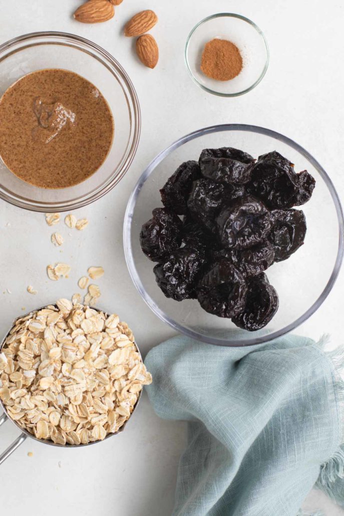 Almond butter, prunes, oat ingredients in bowls with a blue napkin