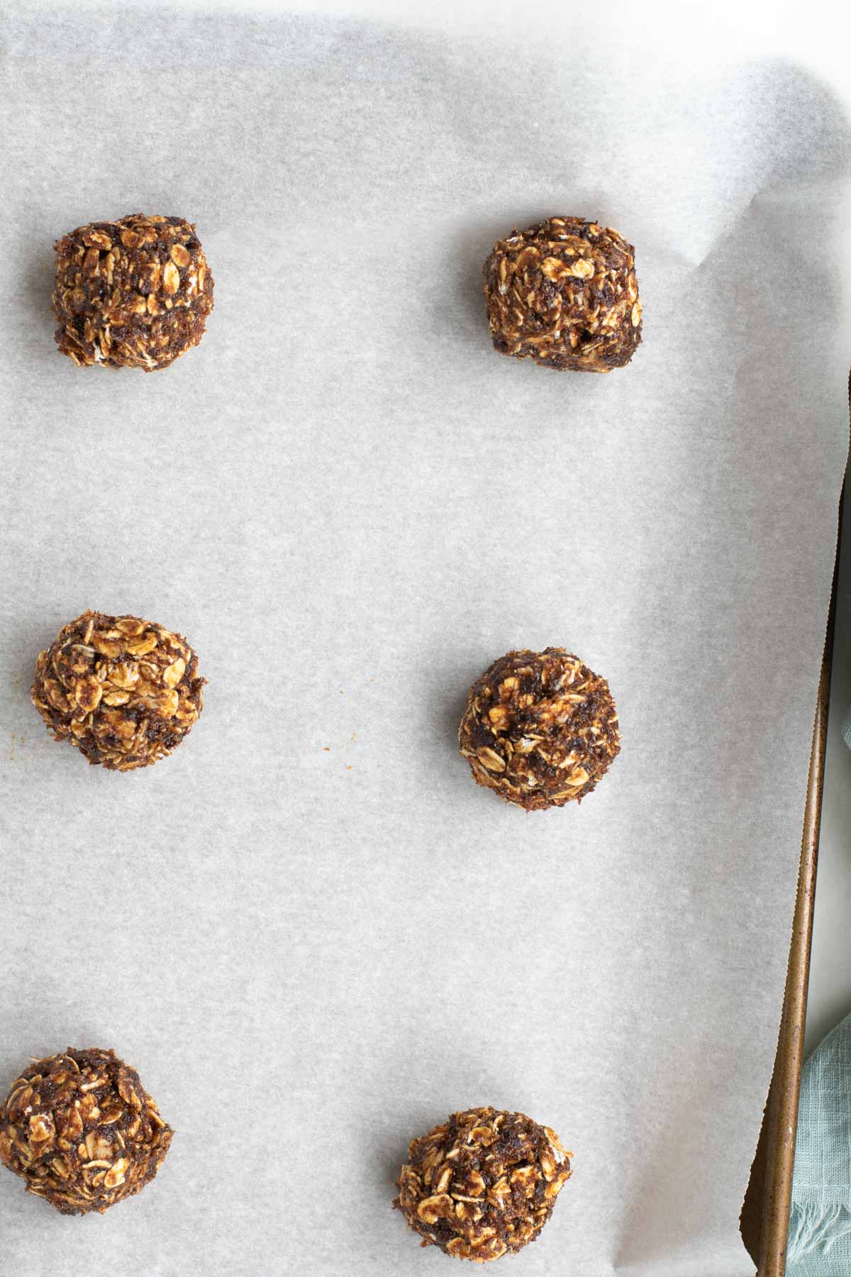 Cookie dough rolled into balls and placed in rows on parchment lined baking sheet.