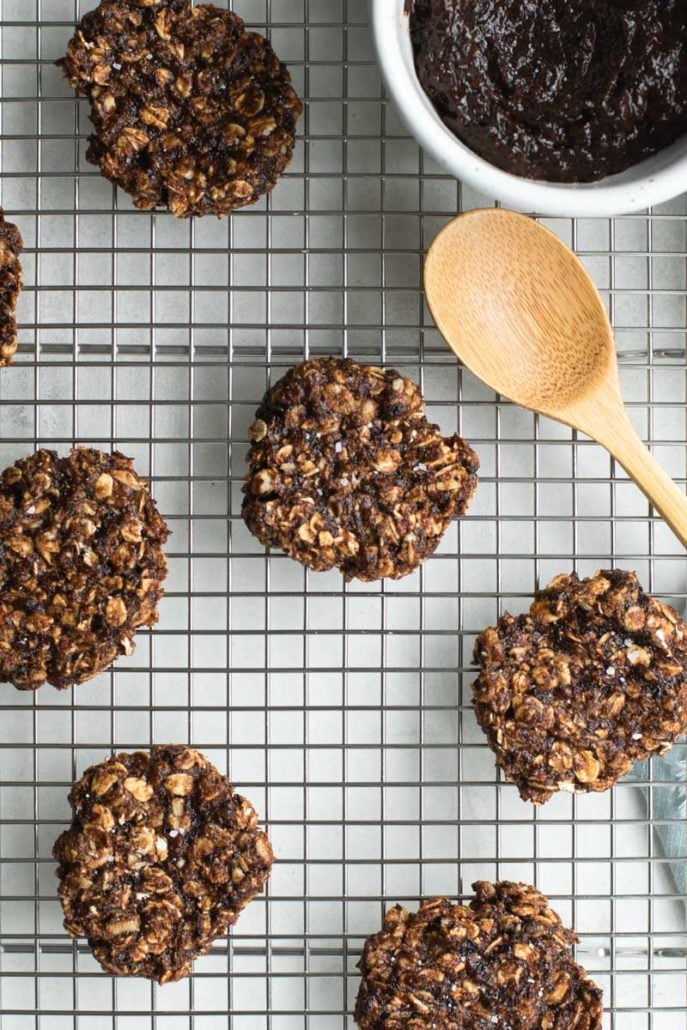 Cookies on a cooling rack with a wooden spoon and ramekin of prune puree.