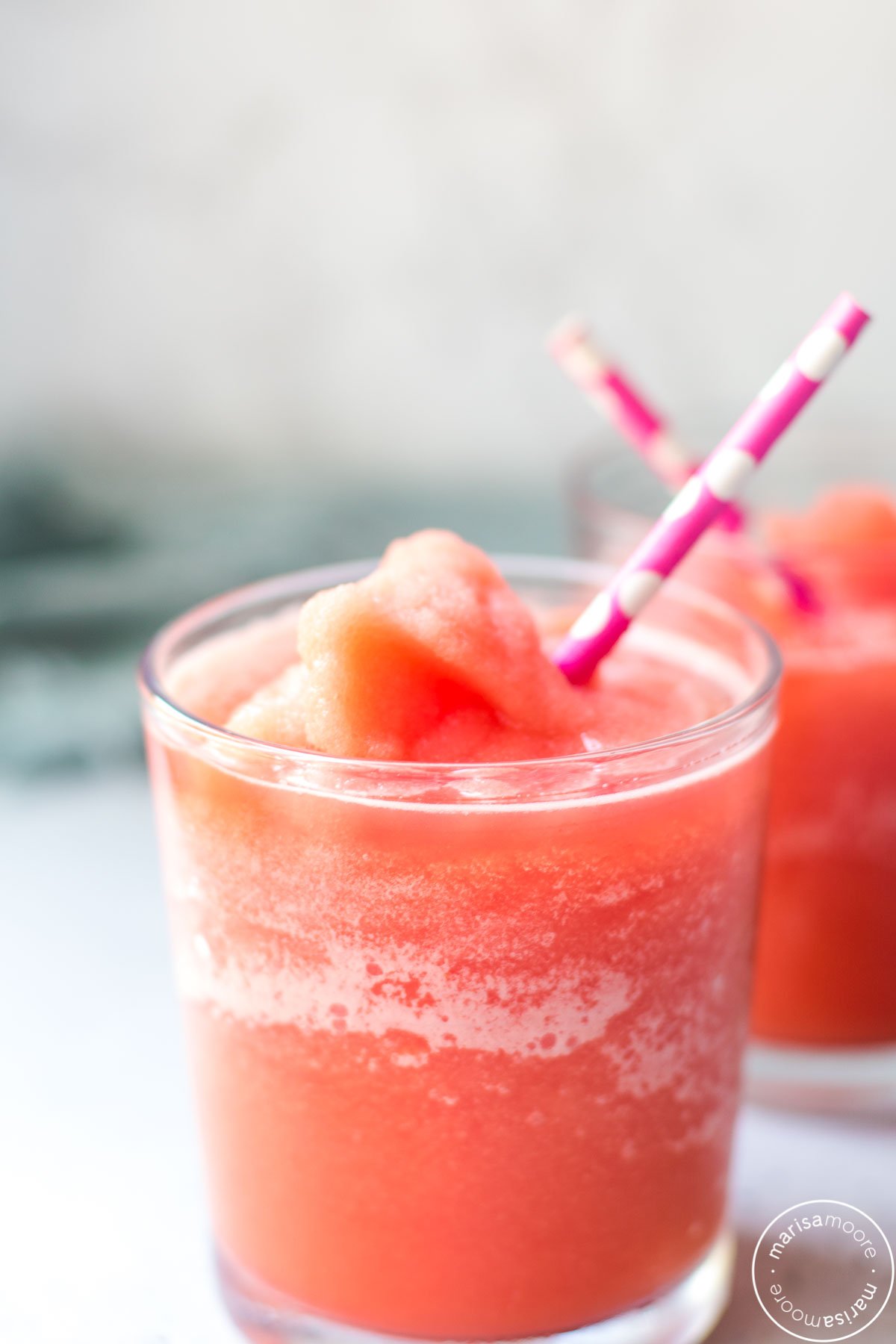 watermelon slushy in a glass with a pink and white straw