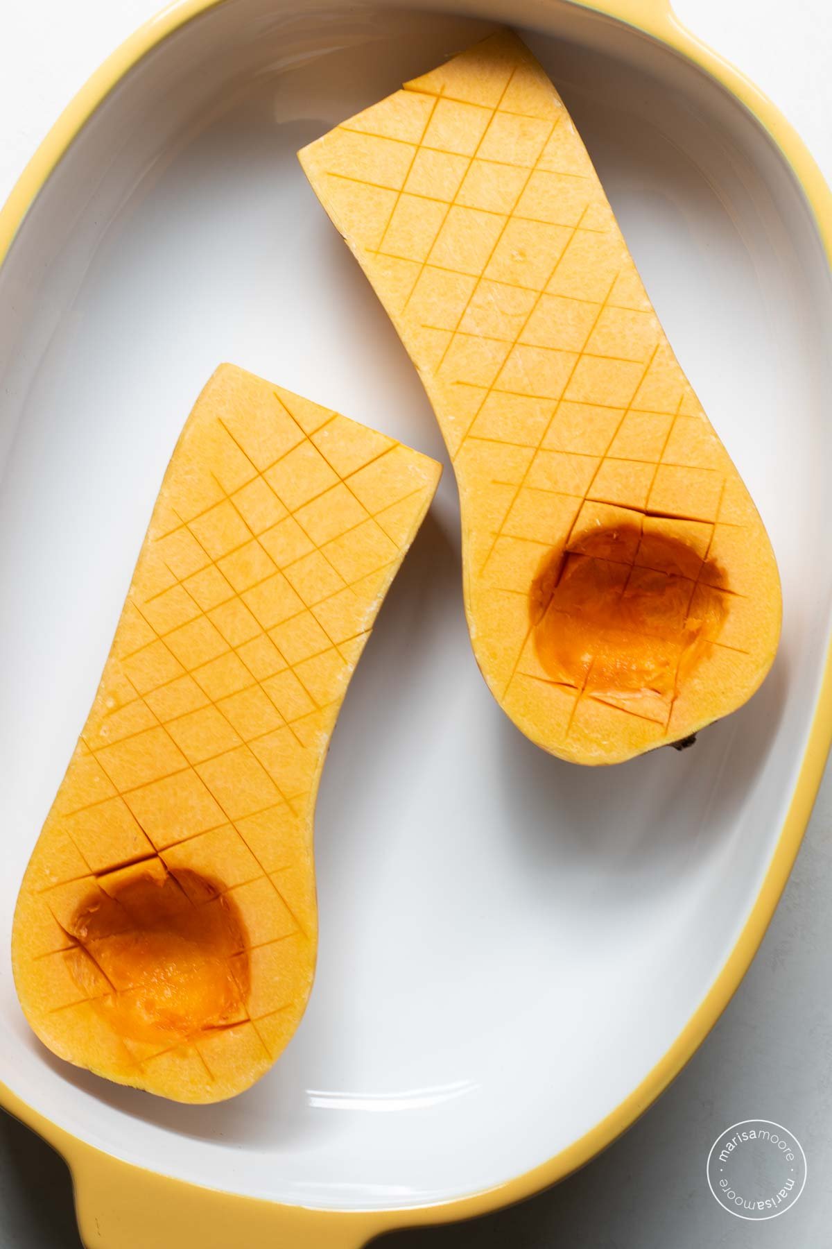 Butternut squash halves in a casserole dish, cut side up.