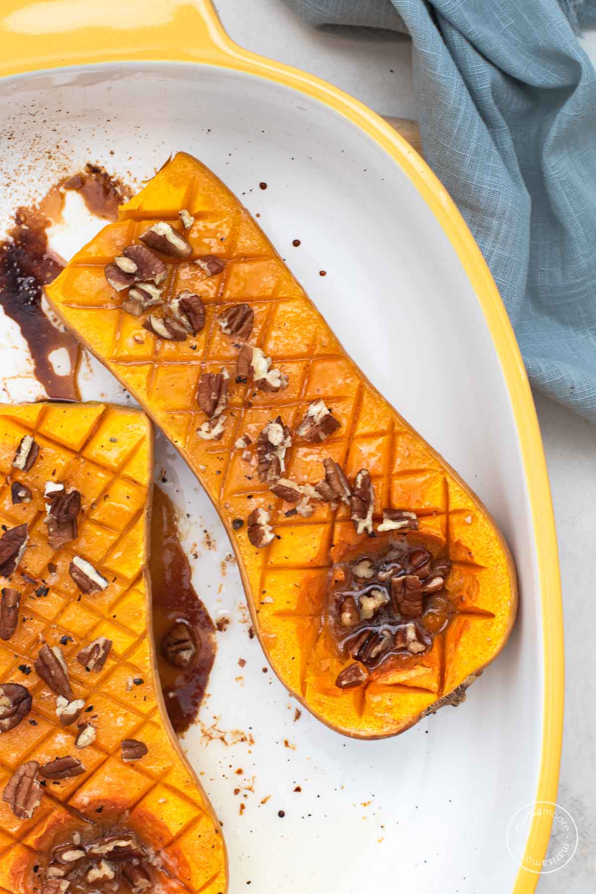 Roasted squash halves with pecans sprinkked on top.