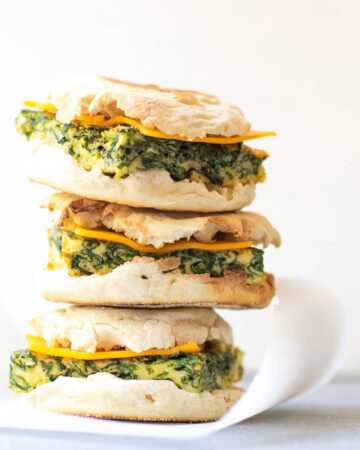 Stack of three spinach egg breakfast sandwiches.