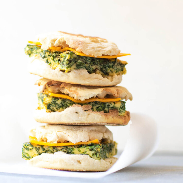 Stack of three spinach egg breakfast sandwiches.