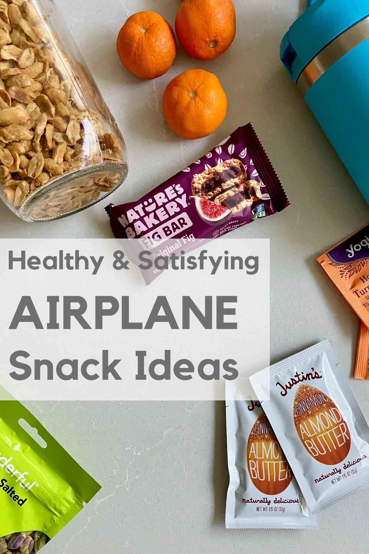 flat lay of peanuts in a jar, tangerines, water bottle, tea packet, fig bar and almond butter packets