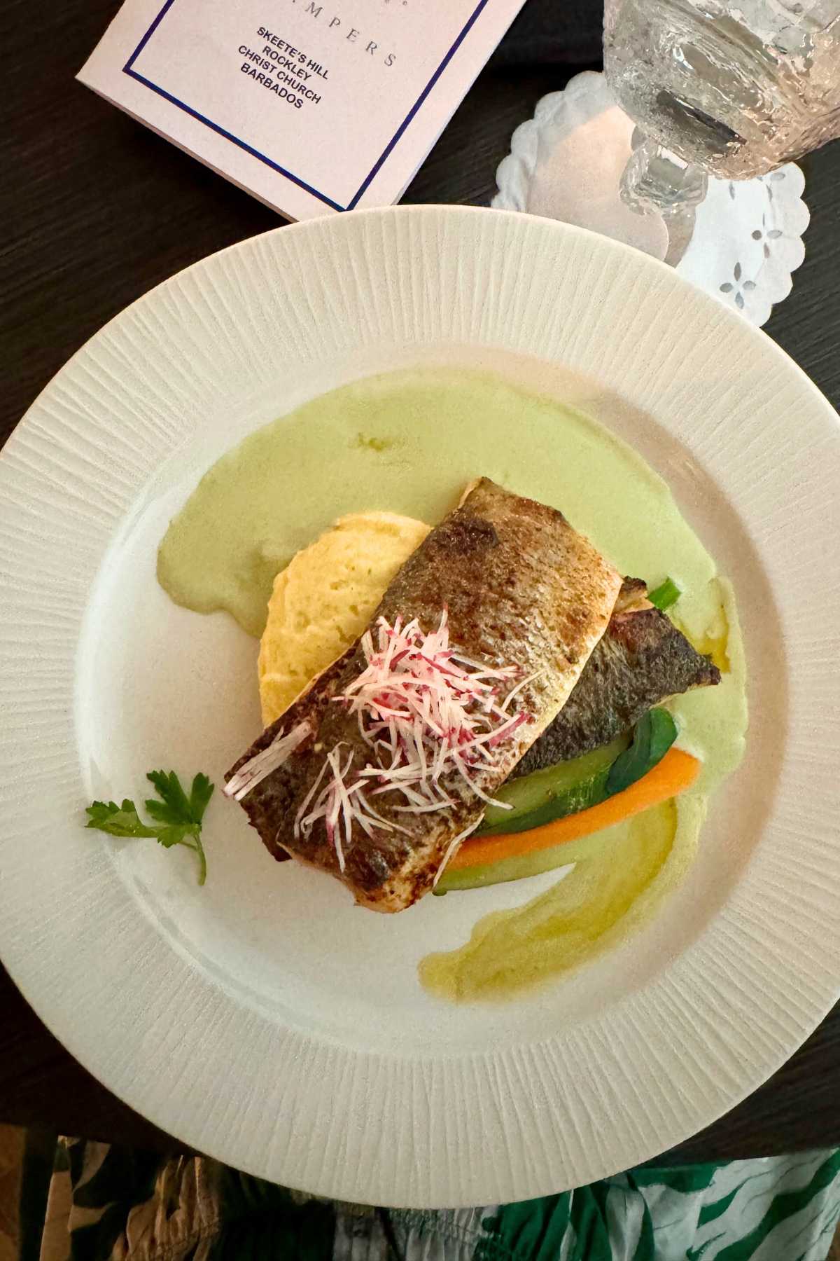 Plated Sea Bass atop vegetables and a green curry sauce at Champer's Restaurant.